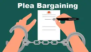 Hands in handcuffs hold a document being signed with