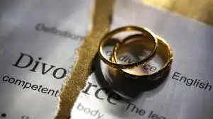 Two gold rings sit on a torn divorce paper, symbolizing separation. The mood is somber with a focus on broken commitment.